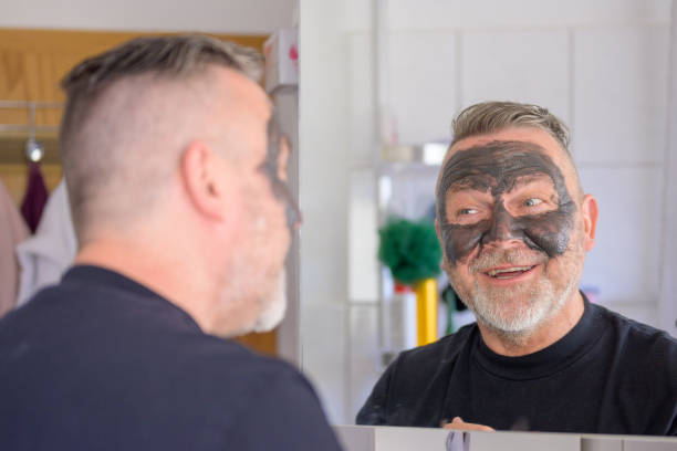 mann, der seine gesichtsmaske in einem badezimmerspiegel auscheckt - airport check in counter stock-fotos und bilder