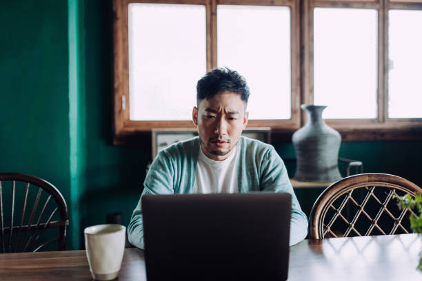 istock Worried young Asian man using laptop computer at home, looking concerned and stressed out 1406318217