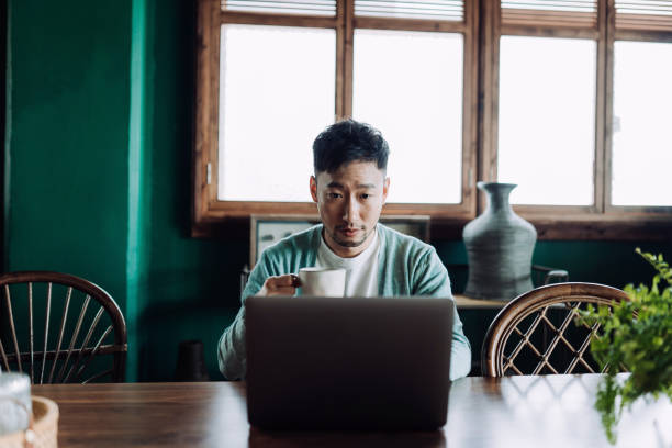 istock Professional young Asian man working from home, using laptop computer in home office. Remote working, freelancer, small business concept 1406318238