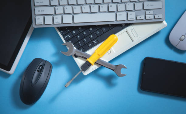 Wrench and screwdriver with a computer keyboard, smartphone, tablet, mouse. IT Service. Support stock photo