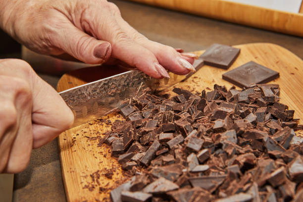 istock Chef cuts bitter chocolate into pieces on wooden board in the kitchen 1406319270
