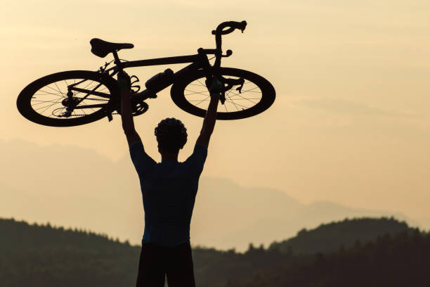 istock Cyclist rising a bicycle above his head and looking at sunset 1406319692