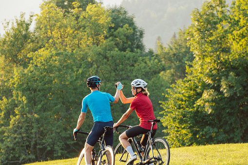 Road cyclists couple taking a ride break along a scenic cycling route enjoying stunning sights and giving high five