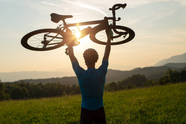 istock Cyclist rising a bicycle above his head and looking at sunset 1406319712