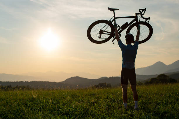 istock Cyclist rising a bicycle above his head and looking at sunset 1406319720