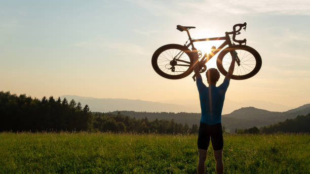istock Cyclist rising a bicycle above his head and looking at sunset 1406319724