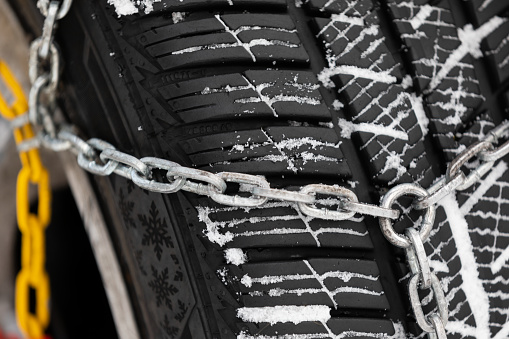 Picture of a vehicle tyre with snow chains on a frozen road