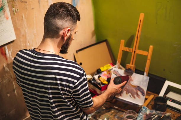 istock Guy in a studio blow-drying a painting of an orange eagle on a canvas 1406320650