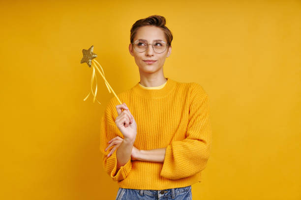 istock Playful woman holding magic wand and looking thoughtful 1406324698