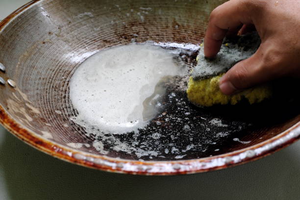 istock Human hand scrubbing or cleaning a burnt, scorched and greasy pan or wok on kitchen sink. 1406330873