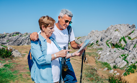 Senior couple with poles hiking looking map outdoors