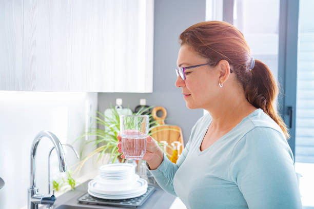 istock Side view of mature woman drinking water in kitchen 1406337798