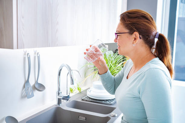 istock Mature woman drinking water in kitchen 1406337802