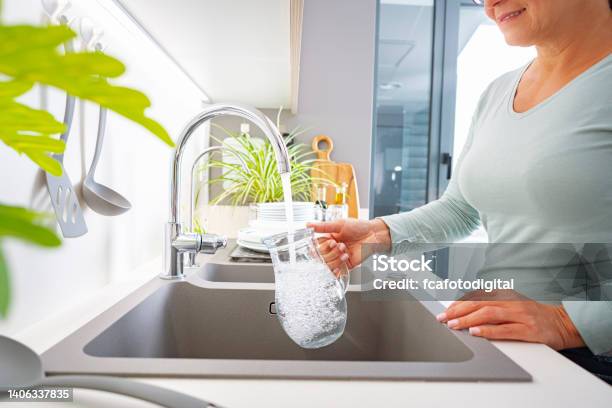Woman Filling Jug With Water From The Tap Stock Photo - Download Image Now - Faucet, Water, Glass - Material