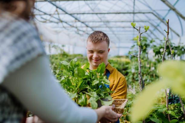 istock Young man with Down syndrome working as a gardener in garden centre 1406343119