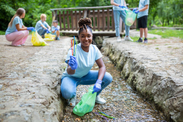 istock Woman handpicking gathering up garbage plastic straws garbage from the river at the park. World environment day.Environment concept. 1406345760