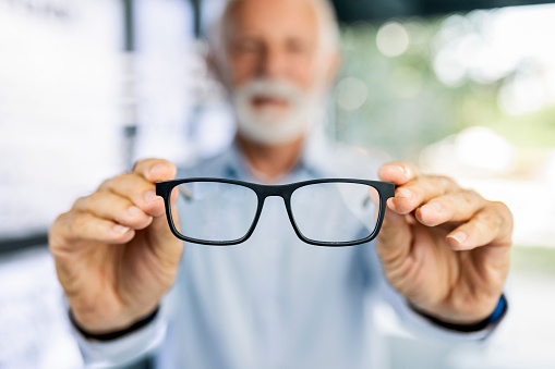 Senior man looking at different new eyeglasses to buy