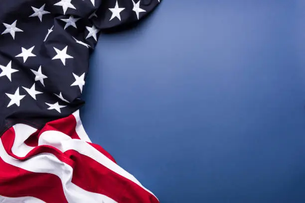 Photo of The flag of the United States of America on blue background with copy space