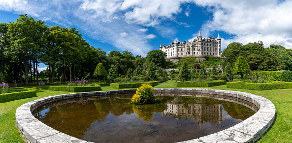 Golspie, United Kingdom - 25 June, 2022: view of Dunrobin Castle and Gardens in the Scottish Highlands and castle reflection in the fountain