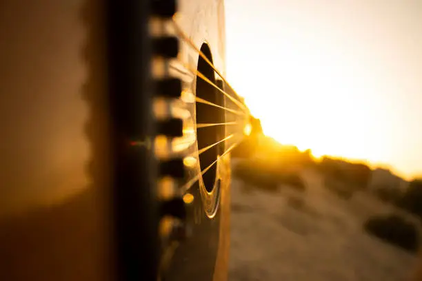 Playing acoustic guitar during sunset with some friends. The image is shown the guitar chords as leading lines that leads the viewer's eyes into the sun.