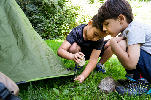 Children nailing tent pegs on a summer camp. learning to pitch a tent. Vacation concept