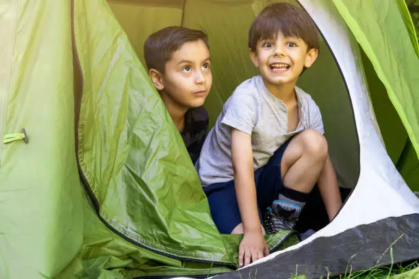 multhietnic latin and caucasian children learning to pitch a tent on a summercamp. Vacation concept