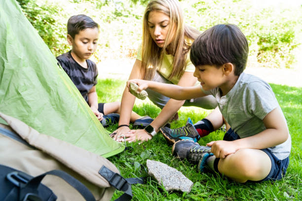 niños latinos y caucásicos multietnicos clavando clavijas de carpa en un campamento de verano con una instructora. aprender a montar una tienda de campaña. concepto vacacional - youth organization fotografías e imágenes de stock