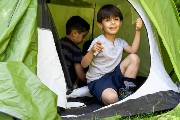 multhietnic latin and caucasian children learning to pitch a tent on a summercamp. Vacation concept