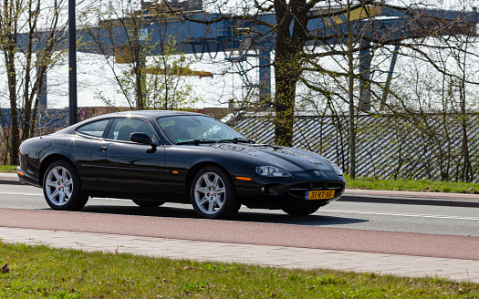 Hengelo, Twente, Overijssel, Netherlands, april 11th 2022, close-up of a Dutch  black 2000 Jaguar XK8 coupe QEV approaching on the 'Boekeloseweg' in Hengelo on a sunny day - the XG-series was made by British manufacturer 'Jaguar Cars' from 1996-2005\n\nThe Hengelo municipality has a population of 82.000 (2022)