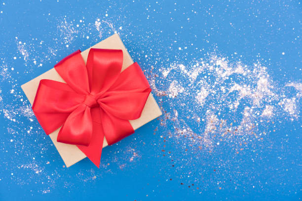 istock Christmas present box with red ribbon bow over blue backgrounds with sparkles around. Beautiful Christmas and New Year festive background with copy space. Gift box 1406359975
