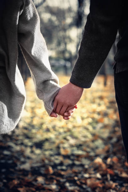 istock Close-up of a couple in love holding hands while walking. Selective focus, vertical 1406360408