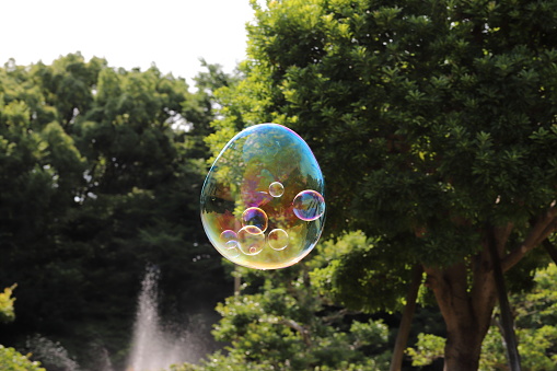 A little boy is playing in the back garden with a giant bubble wand.