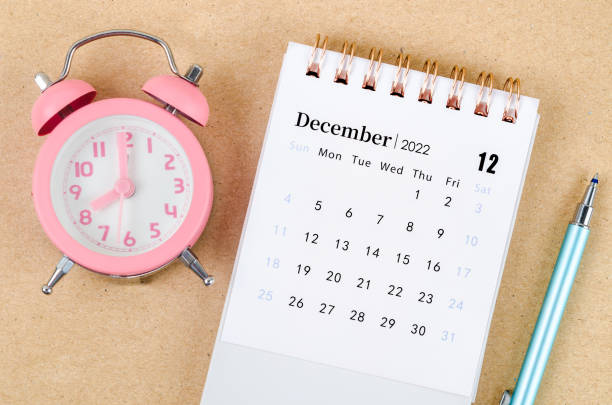 istock December 2022 Desk calendar with pink alarm clock on brown background. 1406363234