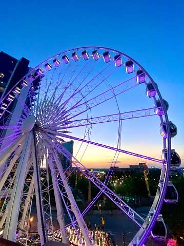 A sunset with a city view and a ferris wheel in the foreground