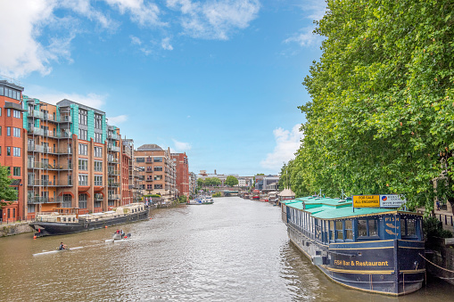 River Avon in Bristol, England - June 19, 2022: People kayaking on River Avon in Bristol. \n\nTo distinguish River Avon from a number of other rivers of the same name, it is often called the Bristol Avon. The name 'Avon' is a cognate of the Welsh word afon, meaning 'river'.\n\nThe Avon is the 19th longest river in the United Kingdom, at 83 miles (134 km), although there are just 19 miles (31 km) as the crow flies between the source and its mouth in the Severn Estuary. The catchment area is 2,220 square kilometres (860 sq mi).