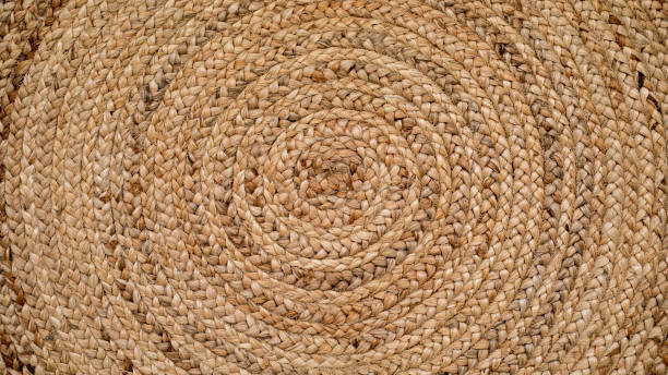 Round natural raffia rug with a spiral braided design and concentric circles Round natural raffia rug with a spiral braided design and concentric circles that creates an ideal texture for backgrounds and graphic resources. raffia stock pictures, royalty-free photos & images