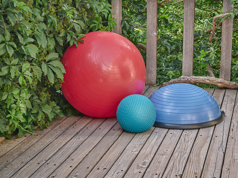 Balance Swiss, bosu and slam training balls on a wooden deck - backyard fitness concept