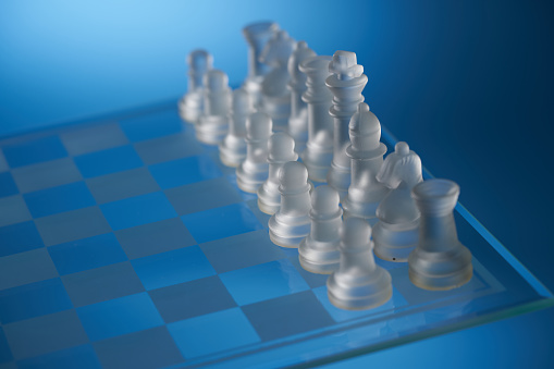 group of glass material chess pieces on chessboard
