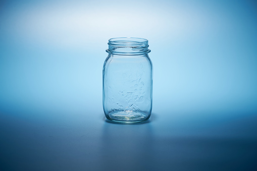 empty glass jar without lid against blue background