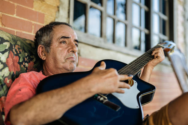 Young man playing acoustic guitar with friend outdoors