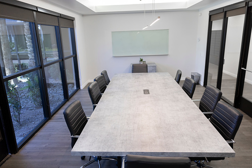 Large conference table with chairs in a meeting room in the high-rise office building, view of the skyline