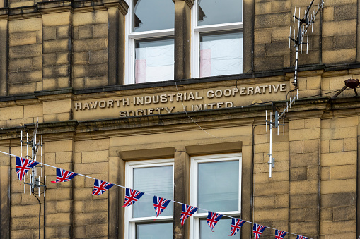 This is historic Haworth, Yorkshire, England, UK, home of the Bronte sisters.  The village is bedecked in bunting and union flags as it celebrates the Platinum Jubilee of Queen Elizabeth II.  This image is of the industrial cooperative society building near the top of the high street.