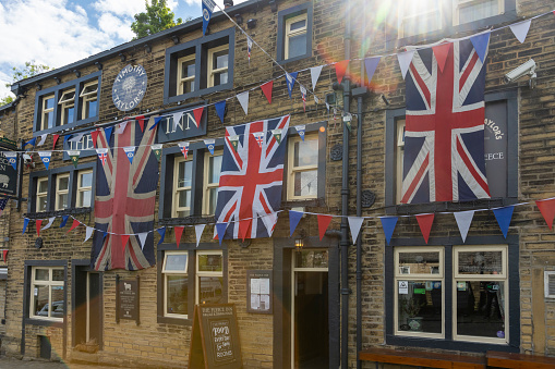 This is historic Haworth, Yorkshire, England, UK, home of the Bronte sisters.  The village is bedecked in bunting and union flags as it celebrates the Platinum Jubilee of Queen Elizabeth II.  This image is of the Fleece Inn, a pub near the top of the high street that took the celebrations especially  seriously.