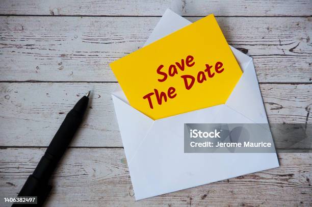 Save The Date Text On Yellow Notepad In An Envelope With Pen And Wooden Desk Background Reminder Concept Stock Photo - Download Image Now