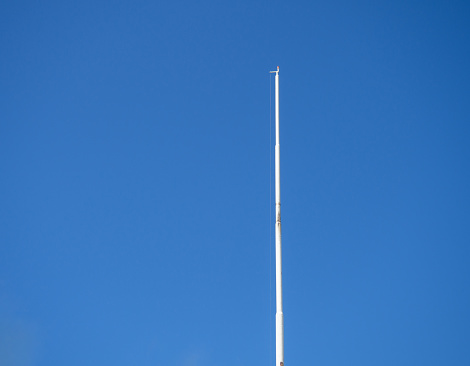 Empty white flagpole against the blue sky. Lowered flag. national