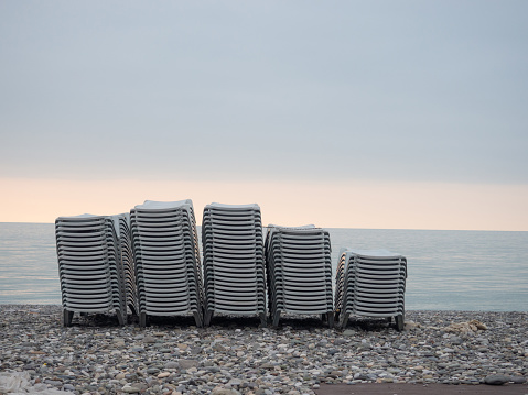 Stacked plastic sun loungers on the beach. Sunbeds in bad weather. Resort in off season. Sea shore