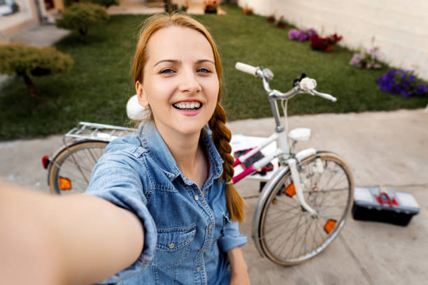 istock Young woman taking selfies while repairing her old bicycle in back yard 1406396723