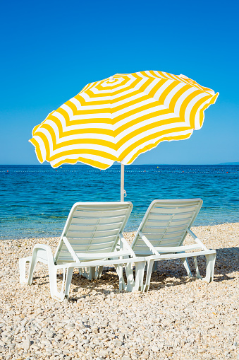 Beautiful beach popular tourist small town of Monterosso in the Cinque Terre Park. The beautiful sandy beach in Italy. Seascape. Striped beach umbrellas on the shore of the Mediterranean sea. Romantic place.