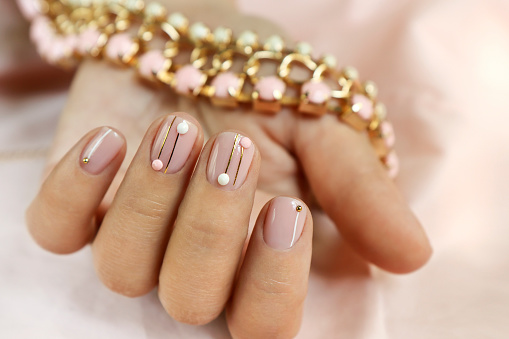 Manicure on short nails with rhinestones and golden lines.