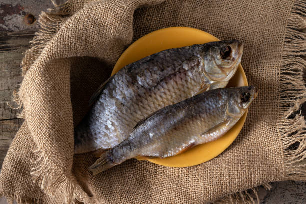 two dried fish - rudd lie on a canvas napkin two dried fish - rudd lie on a canvas napkin common rudd photos stock pictures, royalty-free photos & images